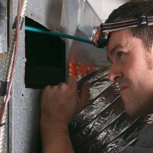 Air duct cleaning specialist doing a visual inspection of furnace ducts