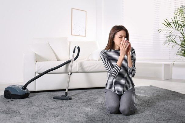 Femme passant l’aspirateur et souffrant d’allergies